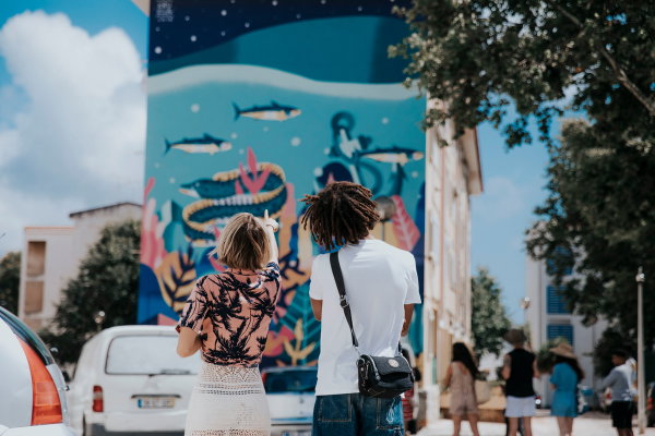 Two travellers admiring a mural on the side of a building