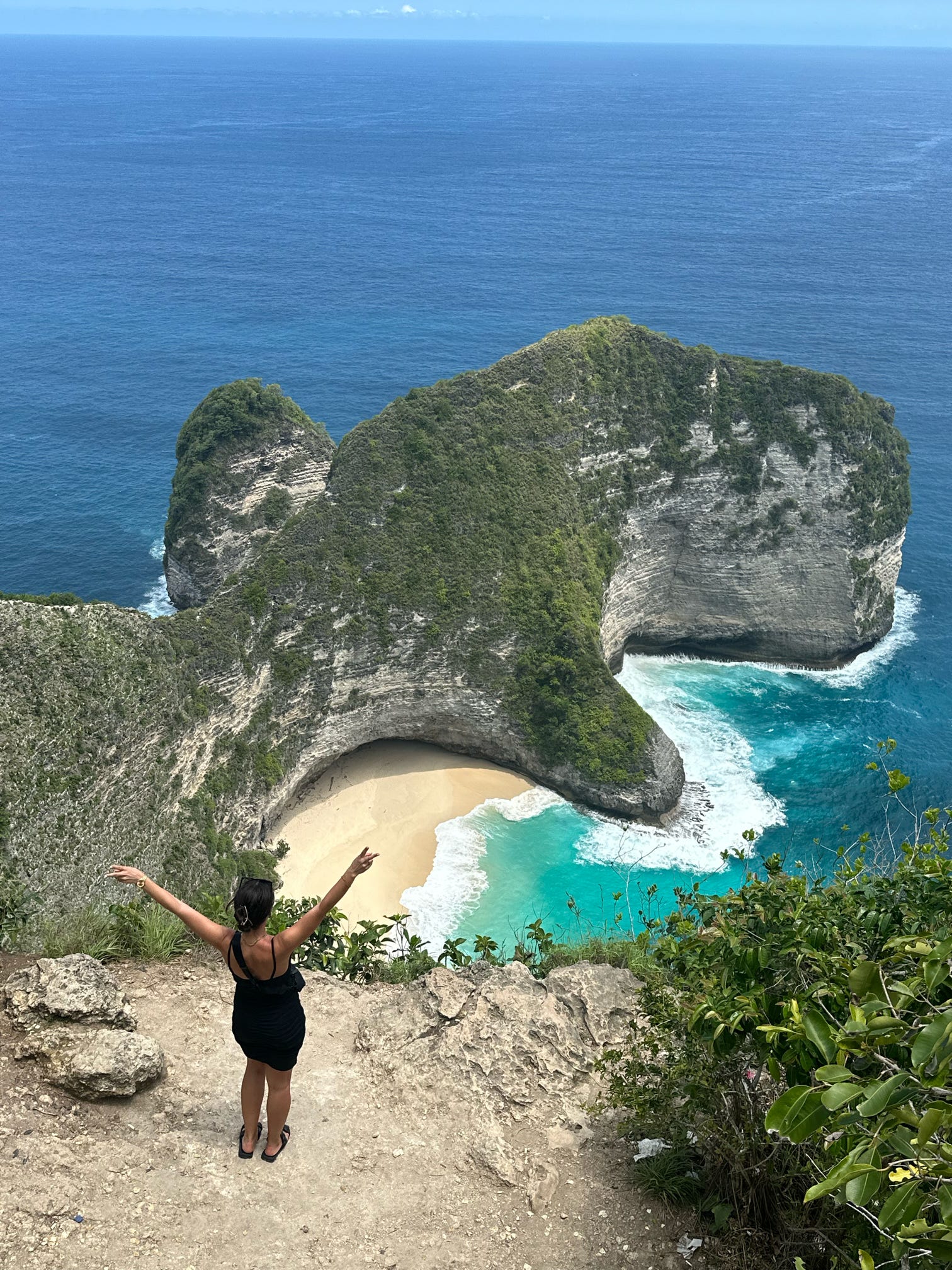 Person with arm's stretched out in front of viewpoint of sea 