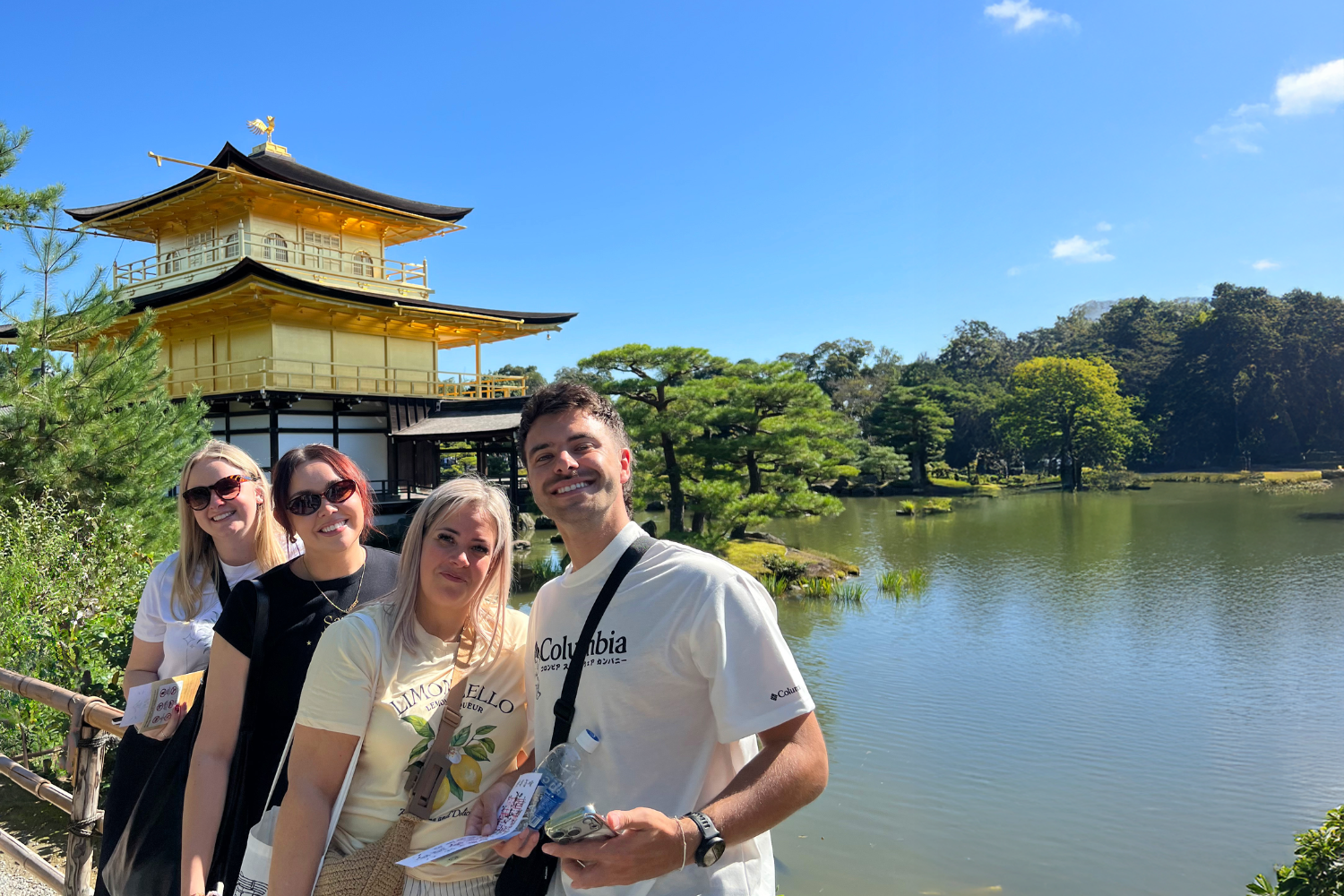Travellers smiling by the Golden Pavillion in Kyoto, Japan