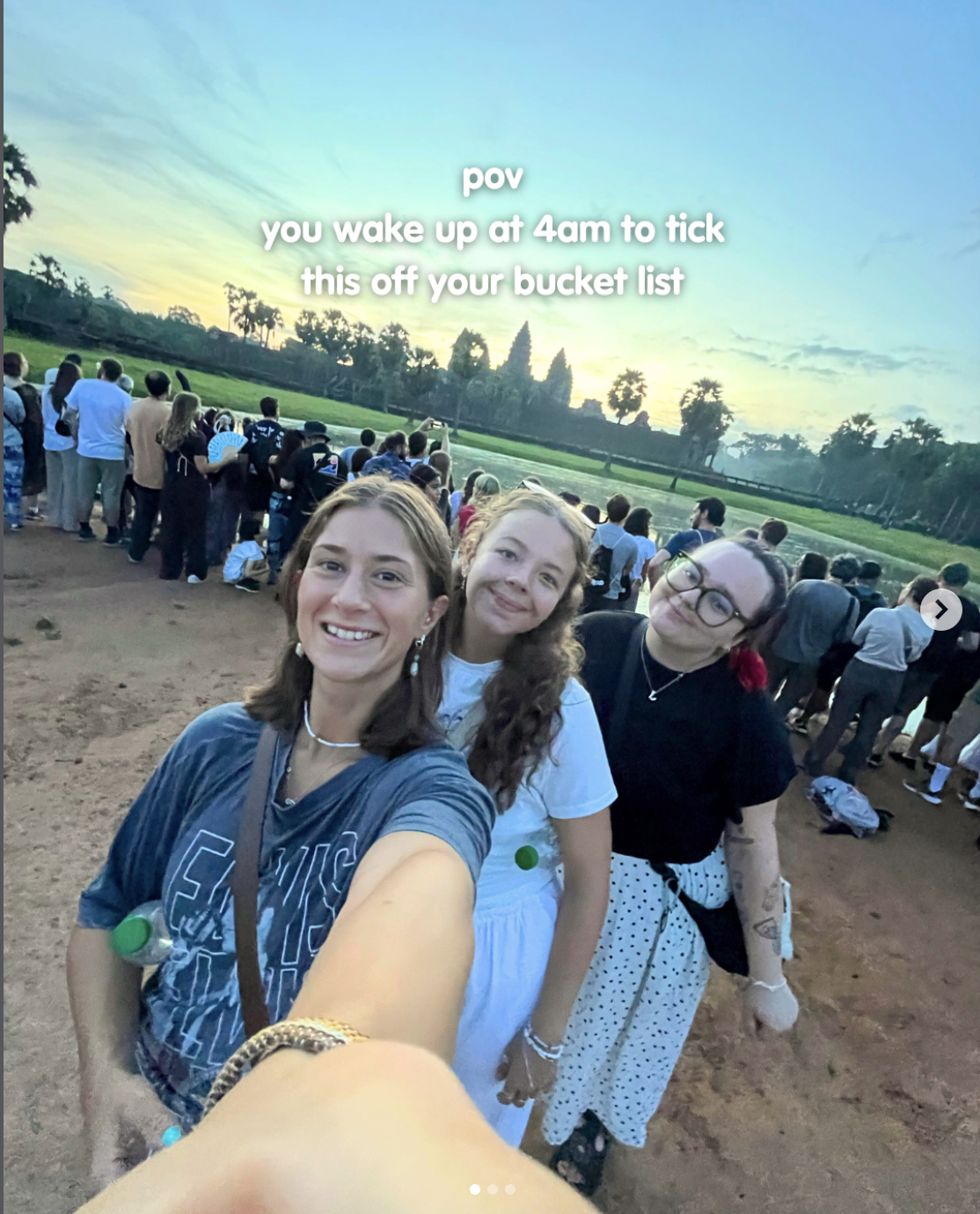 Travellers taking a selfie in front of Angkor Wat at sunrise