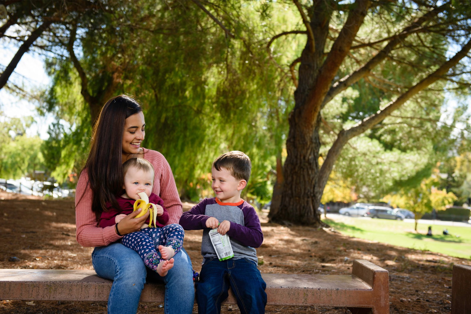 au pair with children in the park eating a snack