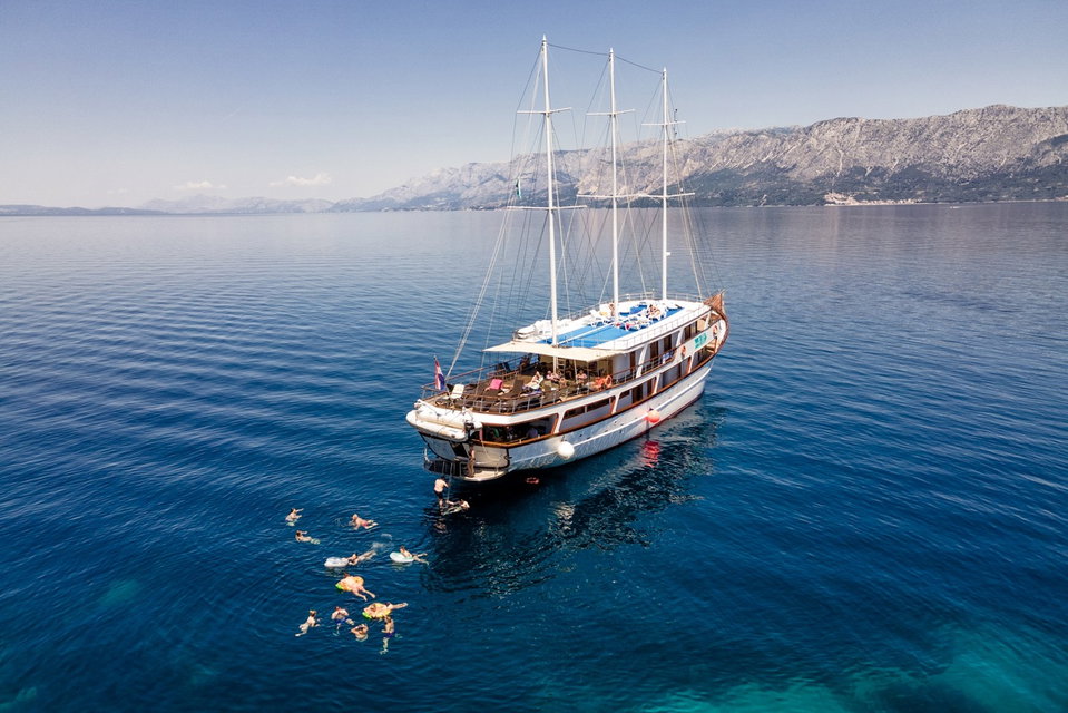 Boat in the Adriatic Sea in Croatia with travellers swimming in the water