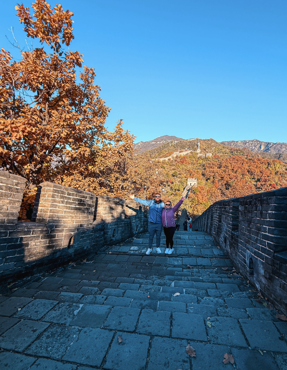 Travellers with their arms in the air on the Great Wall of China