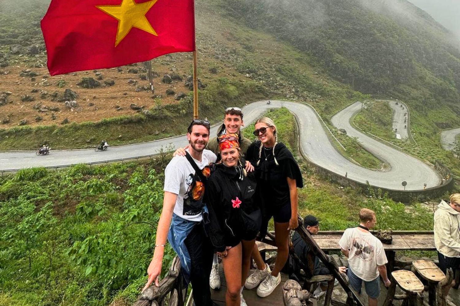 Travellers smiling at viewpoint on Ha Giang Loop in Vietnam with Vietnamese flag