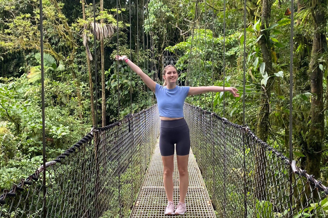 Traveller on suspension bridge in green rainforest with lots of trees, Costa Rica
