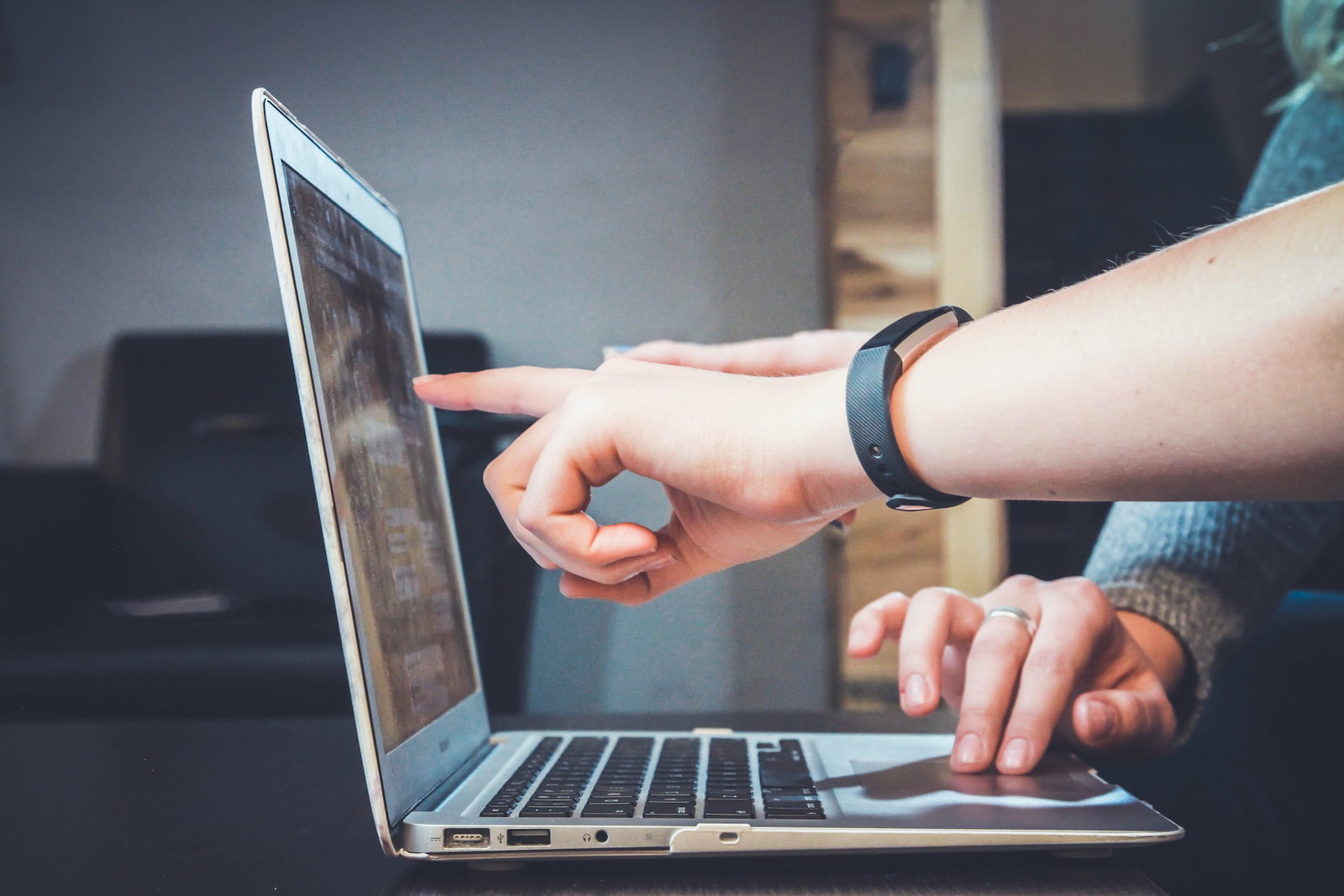 Hand pointing to a laptop screen