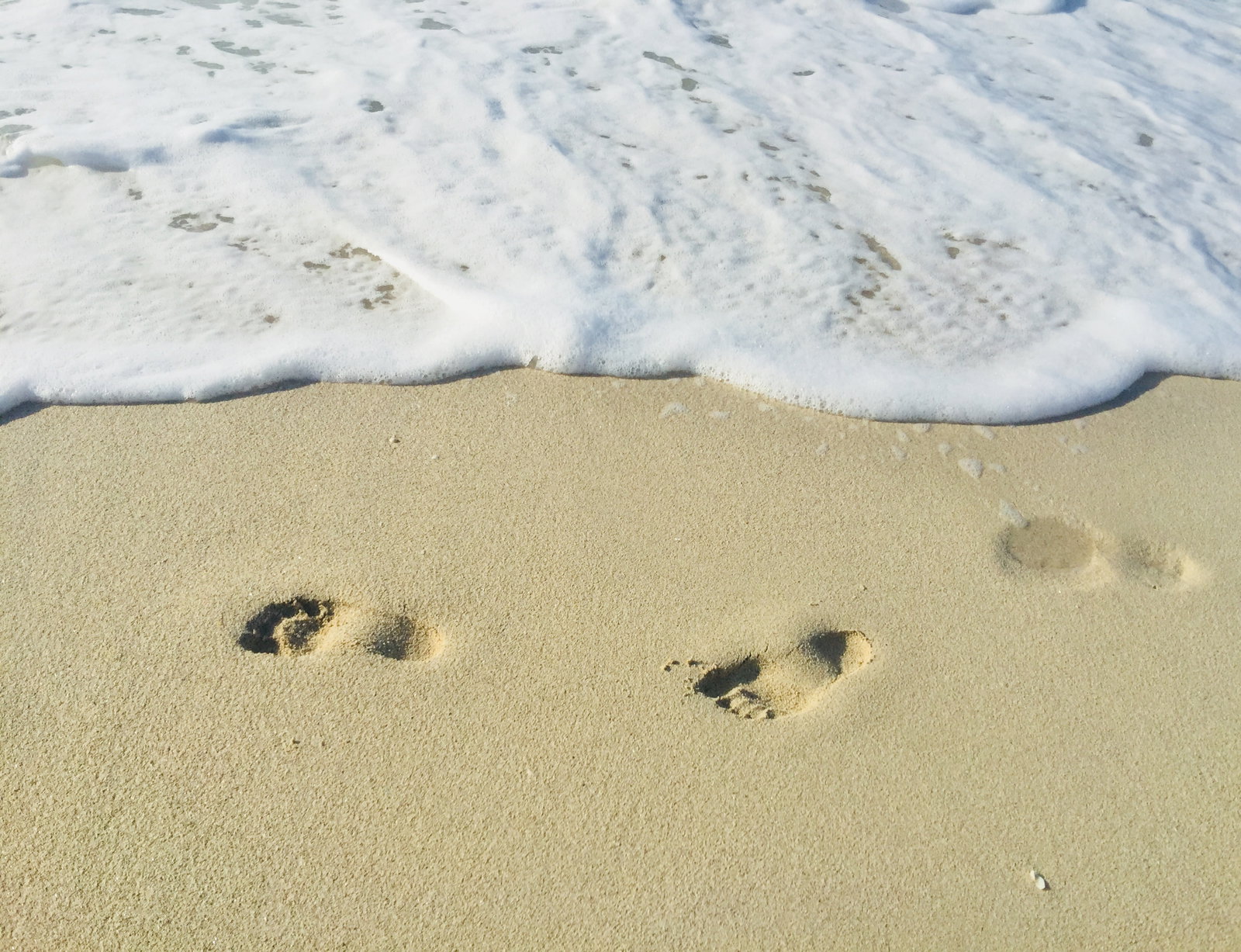 Footsteps in the sand in front of the sea
