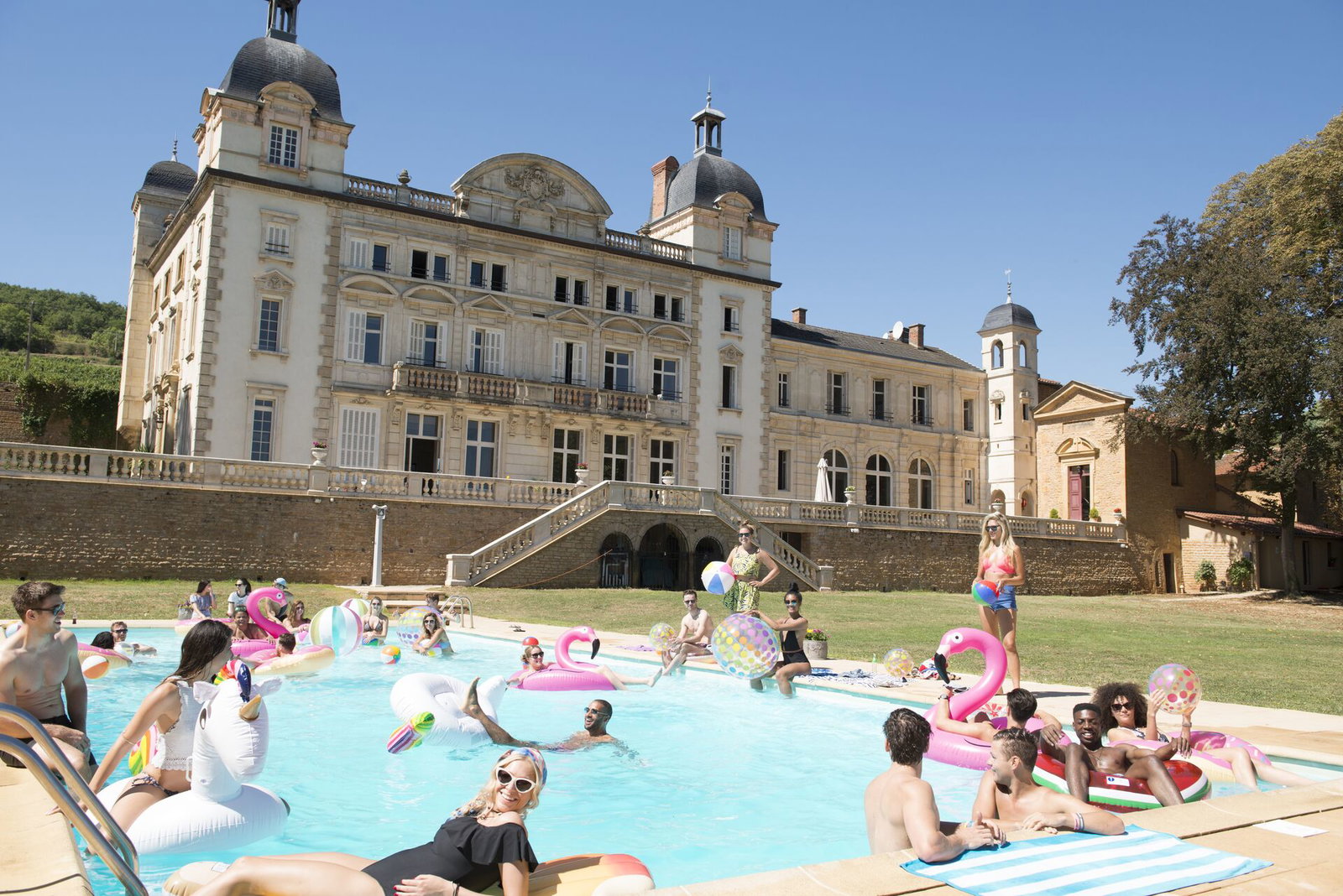 Travellers in chateau in pool with inflatables in France