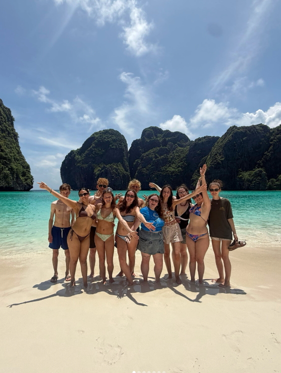 Travellers with their arms in the air on Maya Bay in Thailand