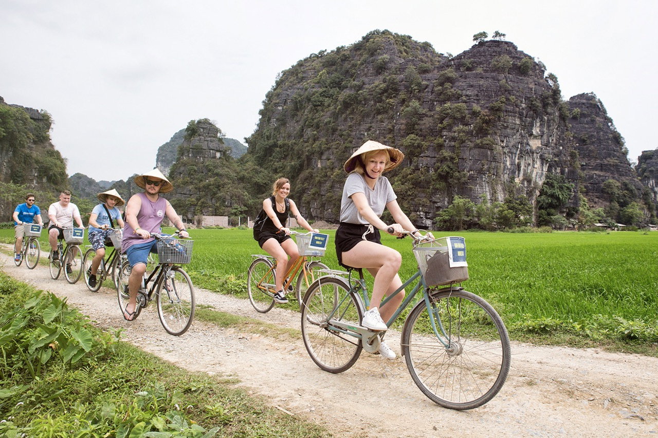 Travellers cycling through Ninh Binh wearing traditional Vietnamese hats