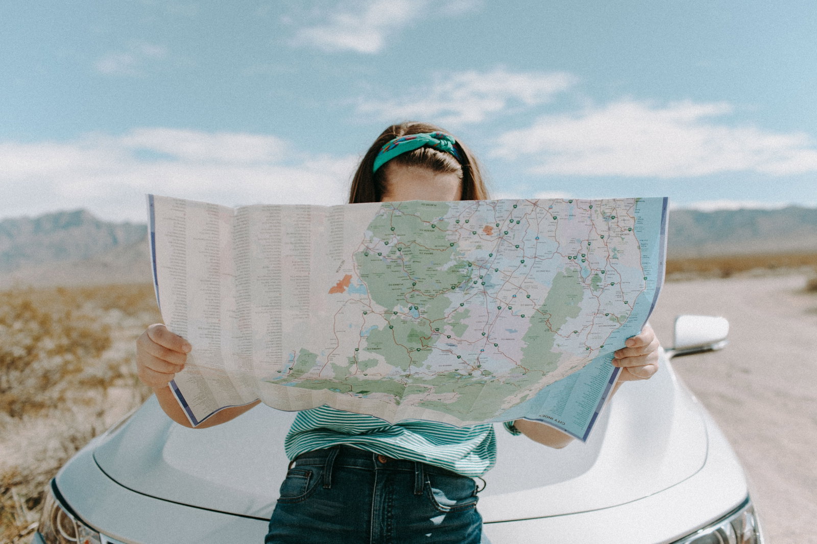 Person reading a map in front of a car