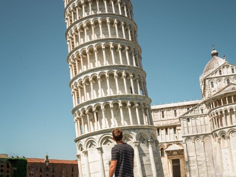 Traveller stood looking up at the leaning tower of Pisa