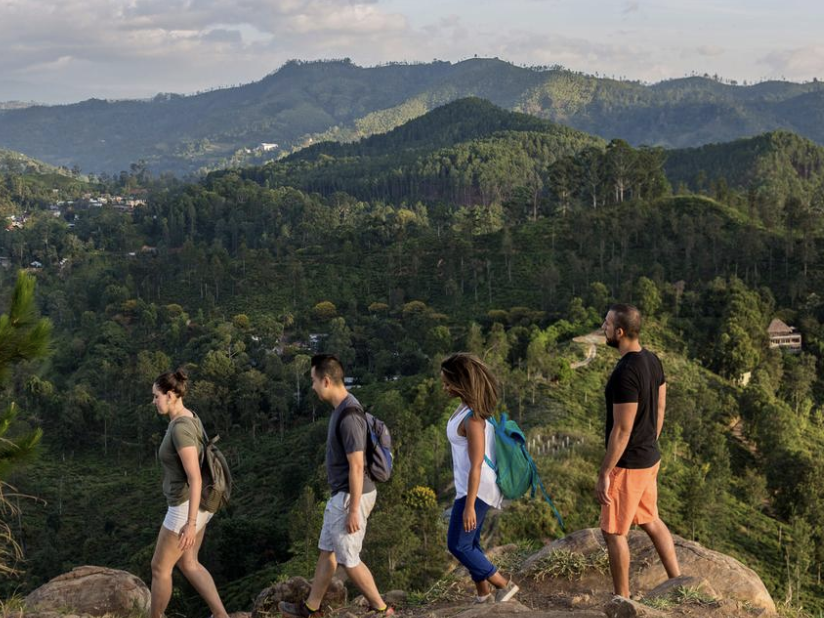 Travellers walking at Little Adams Peak at sunrise in Ella