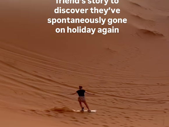 Traveller sandboarding down dune in the Sahara Desert