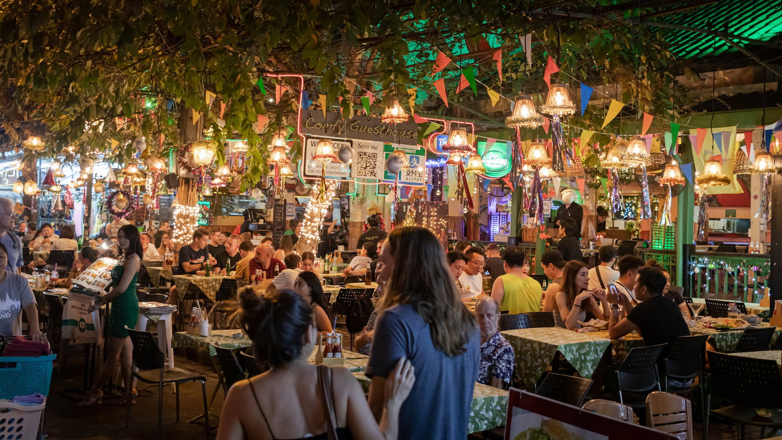 Two travellers looking at an outdoor seating area at a restauraunt on Khao San road