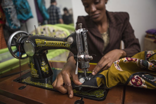 African woman sewing colourful clothes with sewing machine