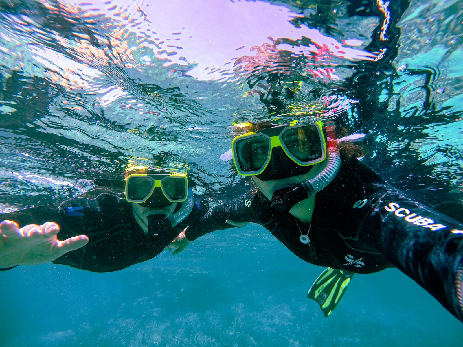 Two persons in snorkelling gear facing the camera underwater