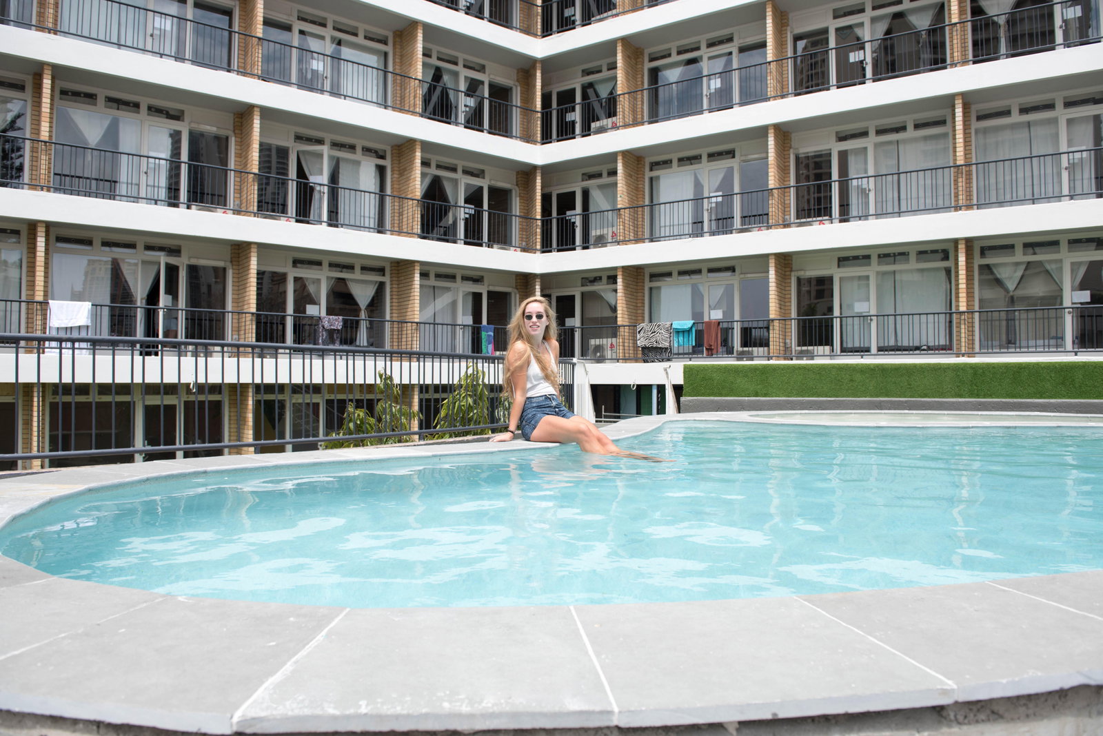 Lady sitting by the swimming pool of a hostel