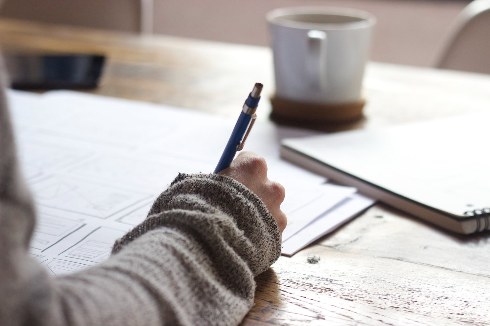 A persons sits at a table writing notes